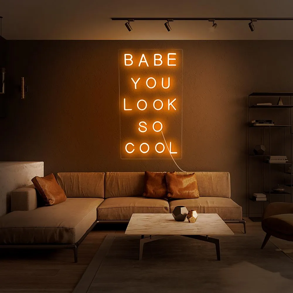 Orange LED neon sign reading Babe You Look So Cool in stacked lines on a living-room wall