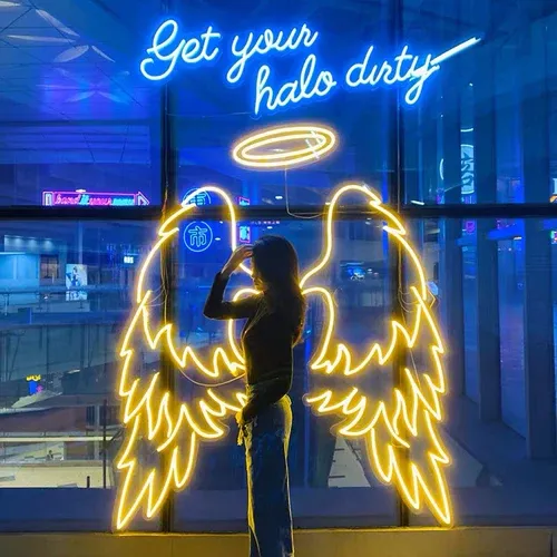 Gold LED neon angel wings with a halo phrase, photographed at an event
